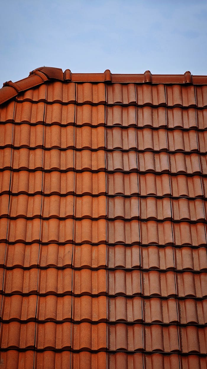 who-we-are Detailed view of classic red clay roof tiles under a clear blue sky.